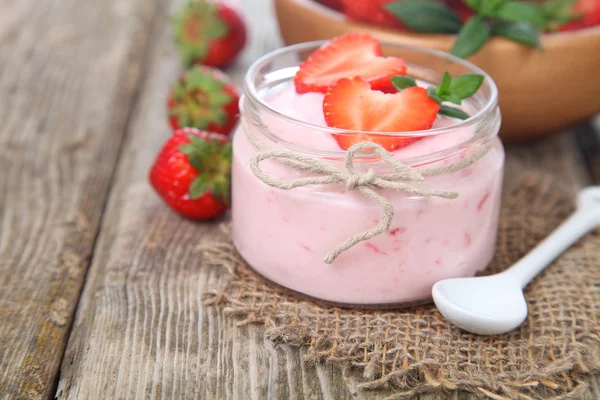 Strawberry yogurt and ripe strawberry on a wooden table