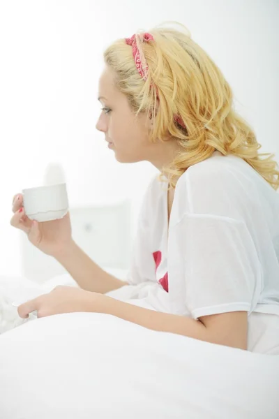 Female on bed in bedroom drinking morning coffee