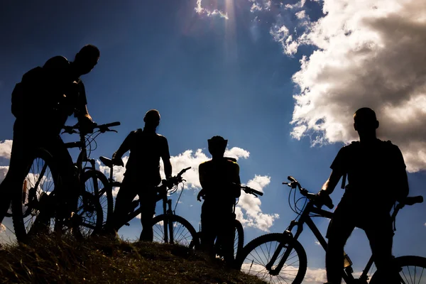 Biking group at sunset sky background.