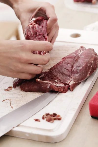 Hands cutting fresh meat