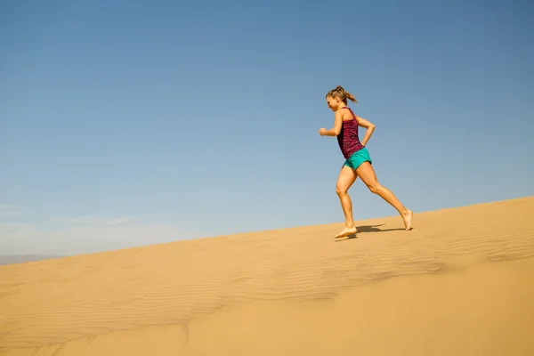 Young woman running on sand desert dunes