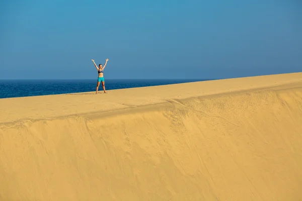 Woman with arms up raised on sand desert dunes