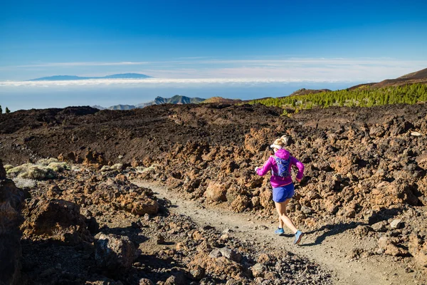 Young woman running in mountains on sunny summer day