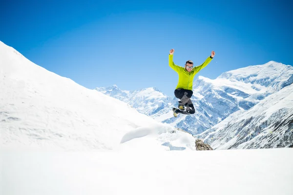 Happy man jumping in winter mountains