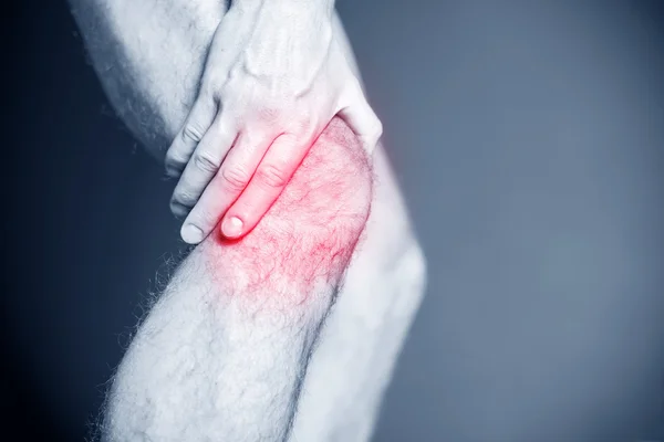 Male athlete holding painful knee, runner injury