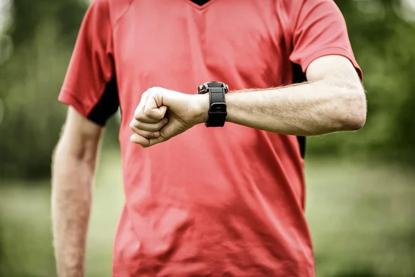 Runner looking at sport or smart watch checking pulse or gps