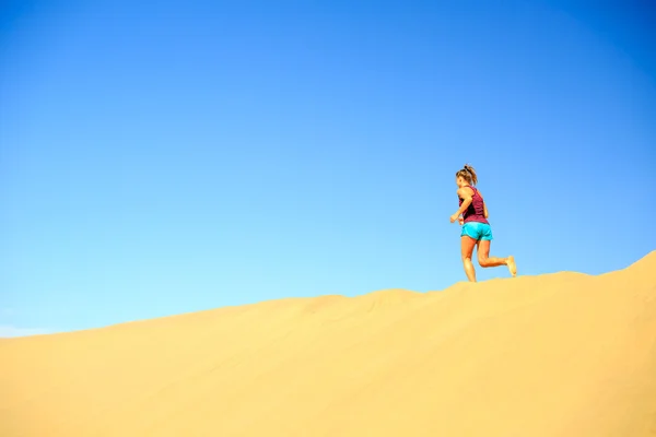 Young woman running on sand desert dunes