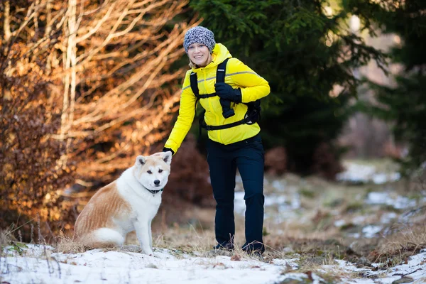 Woman hiking in winter forest with dog