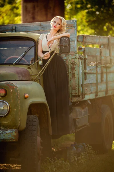 Beautiful woman posing near old truck
