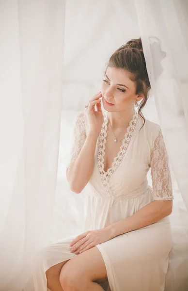 Beautiful brunette girl in white bedroom