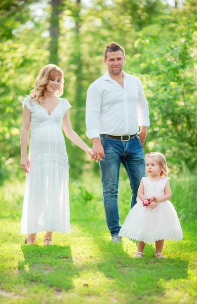 Pregnant woman with her husband and daughter in garden