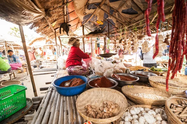 Burmese woman selling spices at asian market.