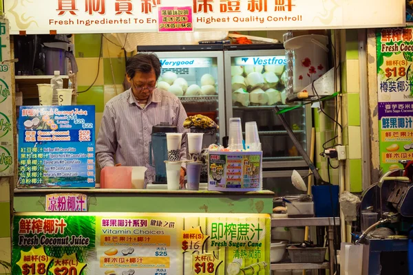 Man selling fresh juice and coconut drink at street shop. Hong K