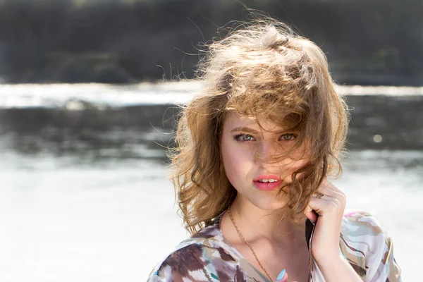 Girl on the bank of the river with developing the wind hair