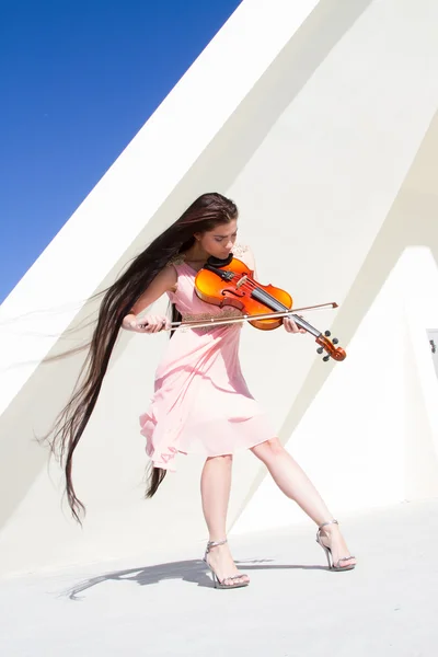 Violinist plays on the stage under the open sky in a pink dress