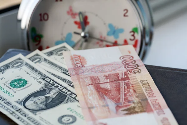 Russian and American money on a background of the alarm. Time is money