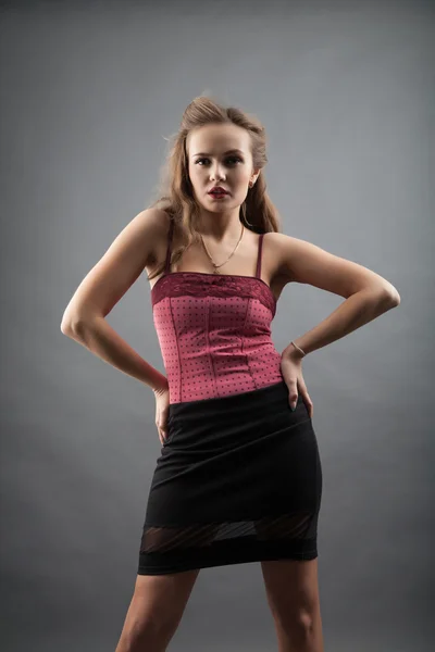 Girl in a short black skirt and pink blouse. studio portrait