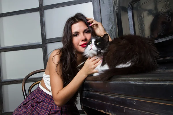 Girl with a cat sitting at the piano