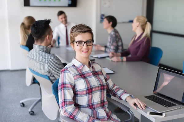 Portrait of young business woman at office with team on meeting