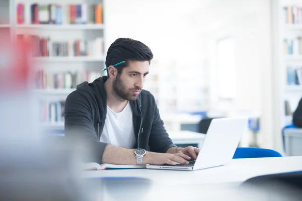 Student in school library using laptop for research