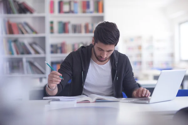 Student in school library using laptop for research