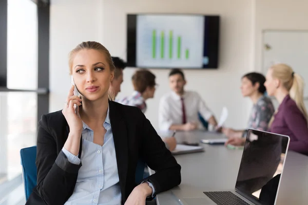 Business woman speeking on phone at office with team on meeting