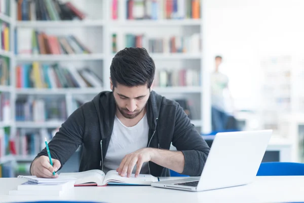 Student in school library using laptop for research