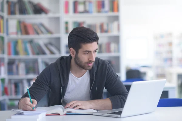 Student in school library using laptop for research