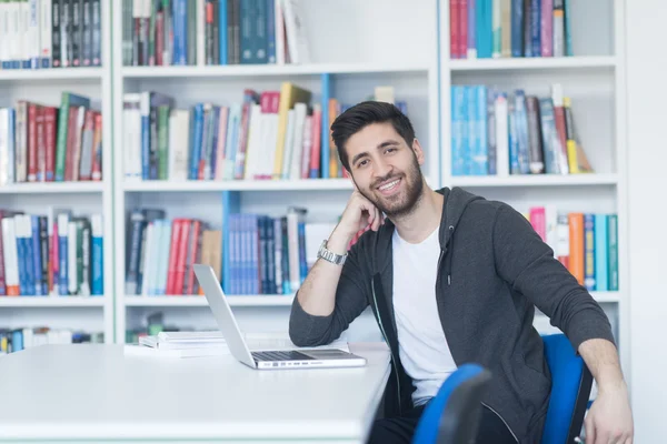 Student in school library using laptop for research