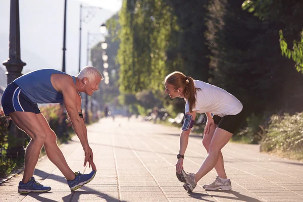 Couple warming up and stretching before jogging