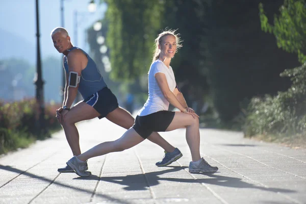 Couple warming up and stretching before jogging