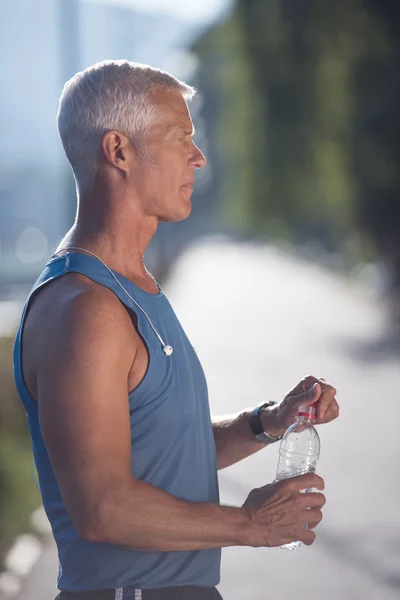 Senior jogging man drinking fresh water from bottle