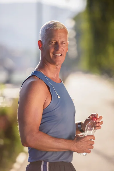 Senior jogging man drinking fresh water from bottle