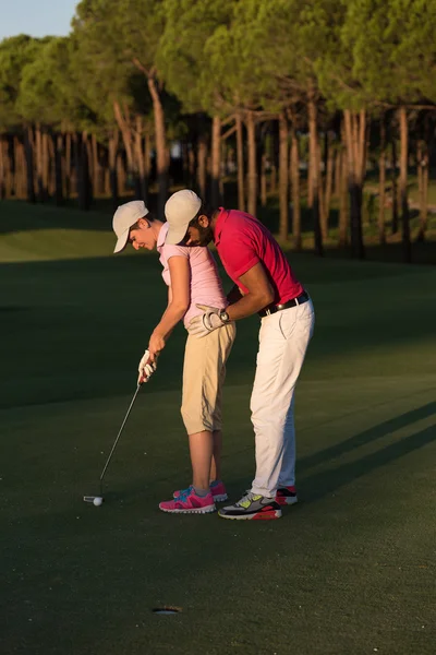Male golf instructor teaching female golf player