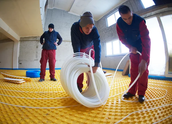 Workers installing underfloor heating system