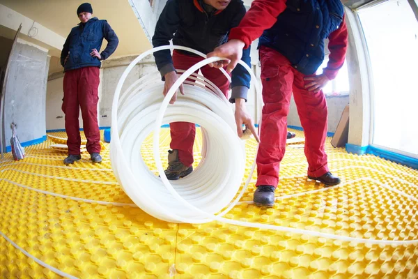 Workers installing underfloor heating system
