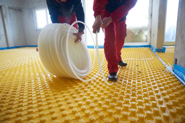 Workers installing underfloor heating system