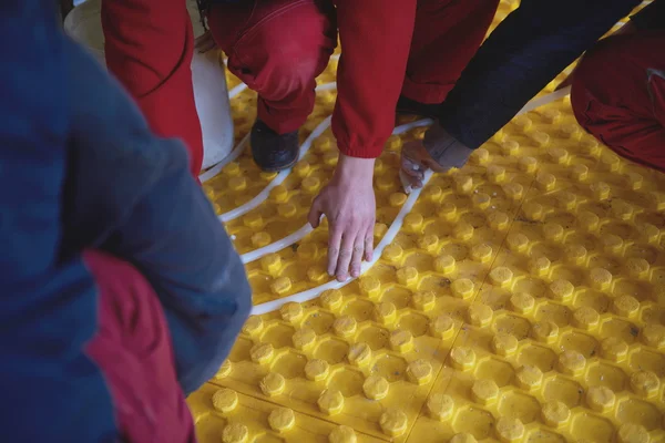 Workers installing underfloor heating system