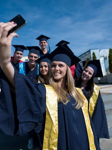 College graduates in graduation gowns making selfie photo