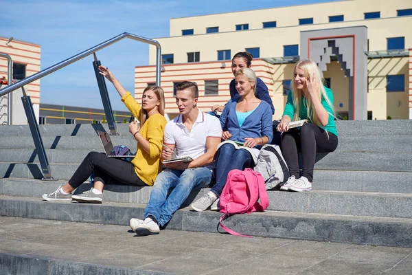 Students outside sitting on steps