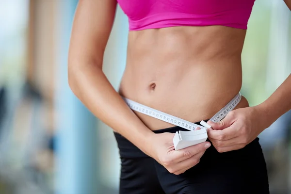 Young fit woman measuring belly