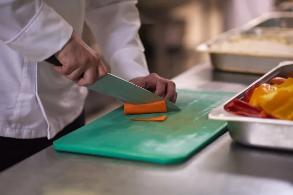 Chef in hotel kitchen slicing vegetables