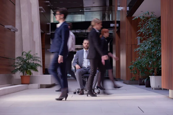 Business man sitting in office chair, people group  passing by