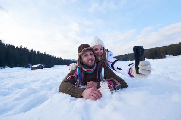 Romantic couple having fun in fresh snow and taking selfie