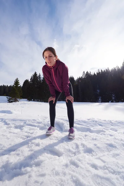 Young woman jogging outdoor on snow in forest