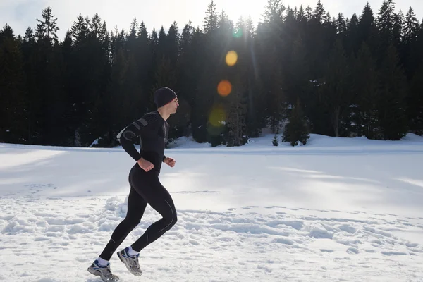 Man jogging on snow in forest
