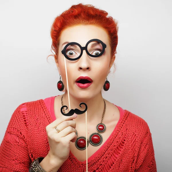 Young woman holding mustache and glasses on a stick.