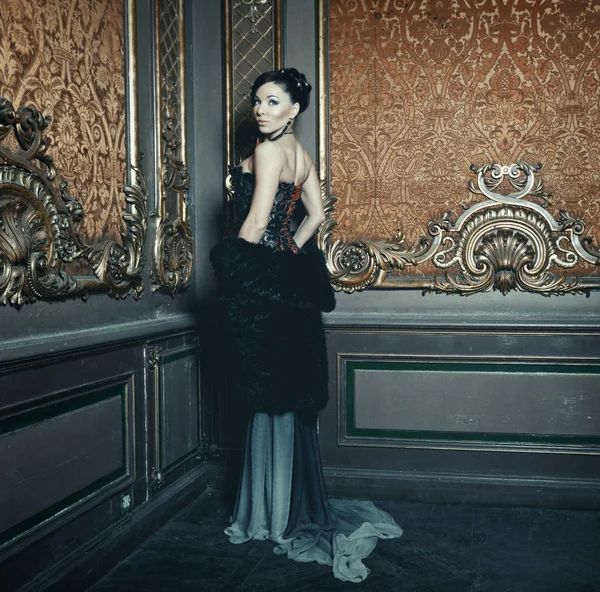 Young beautiful woman standing in the palace room