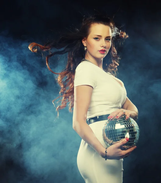Young woman holding disco ball at night club