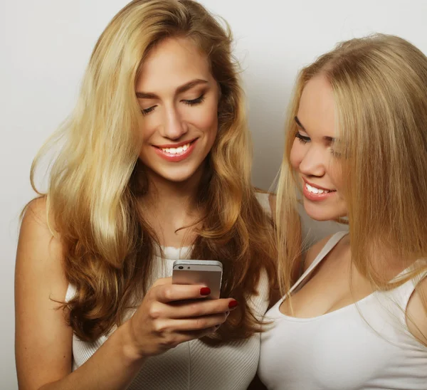 Two happy women friends sharing social media in a smart phone